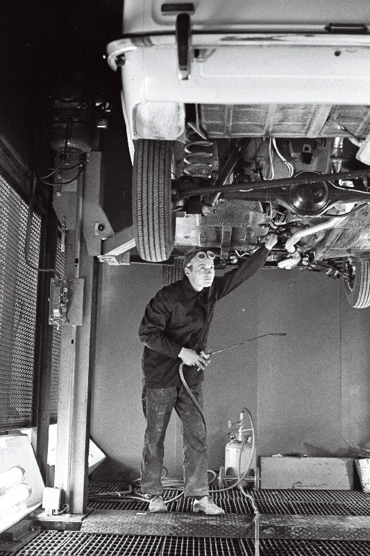 Volga Autotehase Tallinna Autokeskuse töötaja Ado Mälton auto põhja mastiksiga katmas.